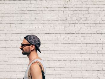 Portrait of young man standing against brick wall