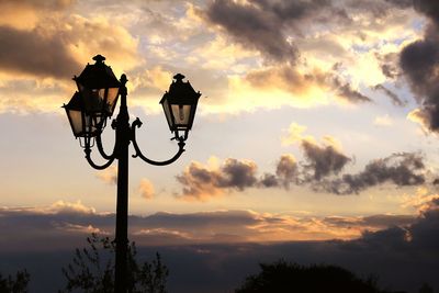 Low angle view of silhouette street light against dramatic sky