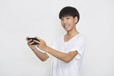 Smiling young man using mobile phone against white background