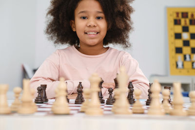 African american girl playing chess happy smiling child behind chess in class or school lesson.