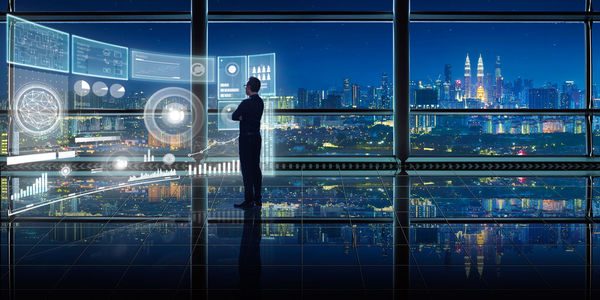 Digital composite image of businessman with icons working in office at night