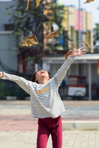 Cheerful girl with arms raised standing outdoors