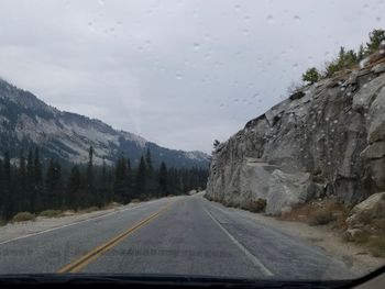 Road amidst mountains seen through car windshield