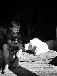 Boy sitting with dog at entrance of house