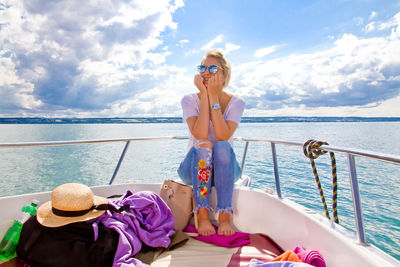 Young woman sailing in boat on sea against sky