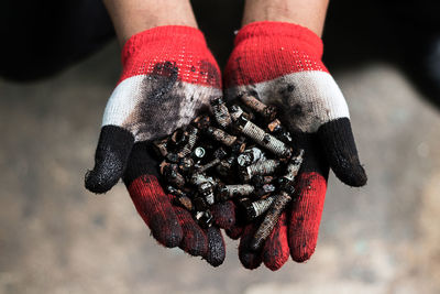 Close-up of hand with gloves holding rusty screws