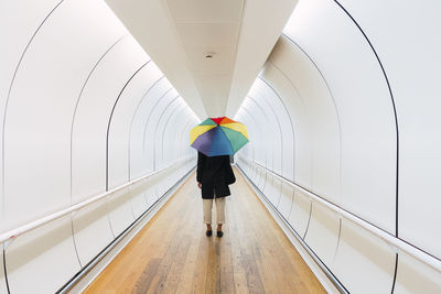 Young woman with umbrella standing on walkway