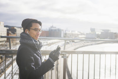 Handsome man with smartphone on footbridge