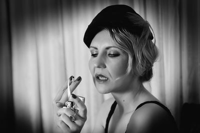 Sensuous mid adult retro woman lighting cigarette at home