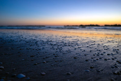 Surface level of beach pebbles against sky during sunrise