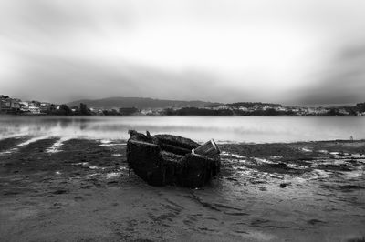 Abandoned boat on beach against sky