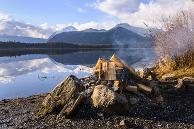 Driftwood on lake by mountain against sky