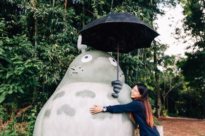 Woman embracing sculpture at park