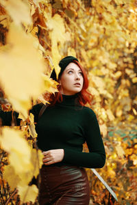 Young woman standing by leaves in autumn