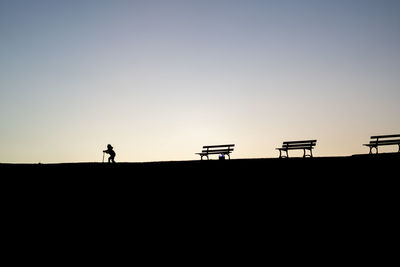 Silhouette man standing on land against sky during sunset