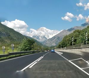 Road leading towards mountains against sky