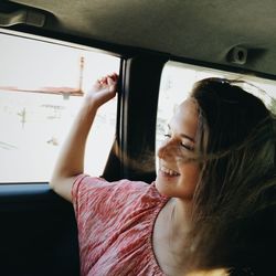 Young woman sitting in car window