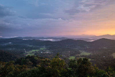 Mountains range misty shadow with dramatic colorful sunset sky at dusk from flat angle