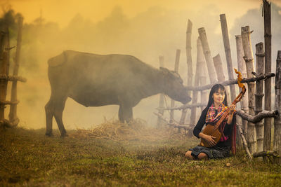 Young woman playing mandolin while sitting in farm