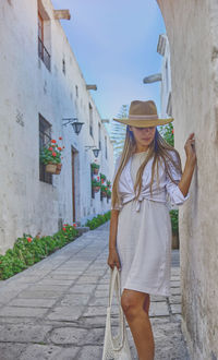 Side view of young woman standing against building