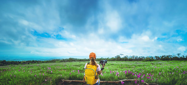 Rear view of woman standing on field against sky