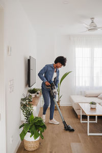 Woman cleaning living room with vacuum cleaner at home