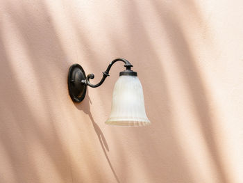 Close-up of electric lamp hanging on wall at home