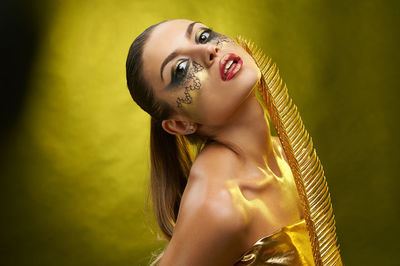 Portrait of a young woman against yellow background