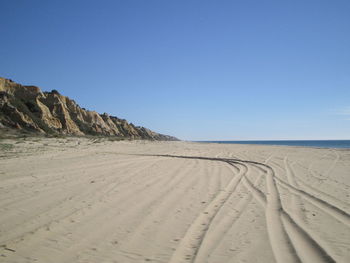 Tracks on beach against blue sky