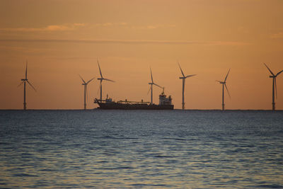 Commercial dock by sea against sky during sunset