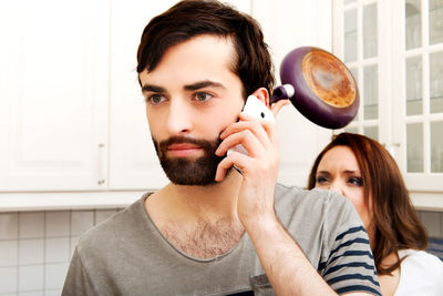 Portrait of young man holding camera at home