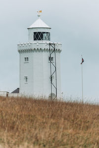 Low angle view of lighthouse on field against sky