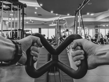 Cropped hands of man exercising while sitting in gym
