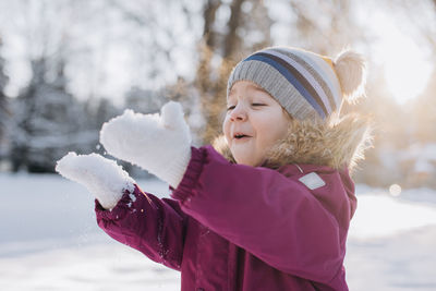 Portrait of smiling young woman standing on snow