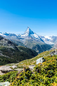 Scenic view of snowcapped mountains against blue sky