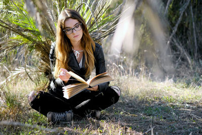 Close-up of teenager reading book while sitting on field