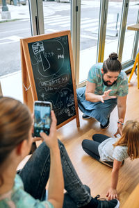 High angle view of woman using mobile phone while sitting on table