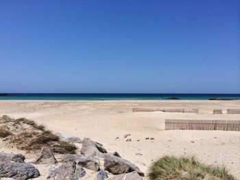 Scenic view of beach against clear blue sky