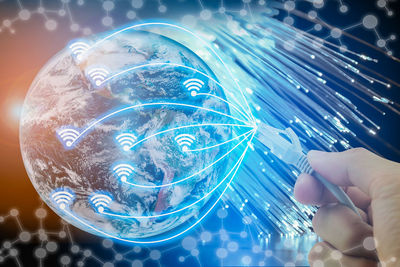 Digital composite image of hand holding cable with icons on globe