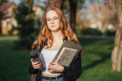 Choosing a university, college. female college student with books and laptop outdoors. redhead