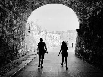 Rear view of people walking in tunnel