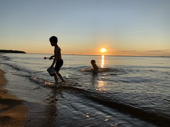 People on beach against sky during sunset