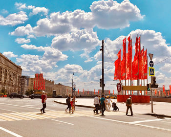 People walking on street in city against sky