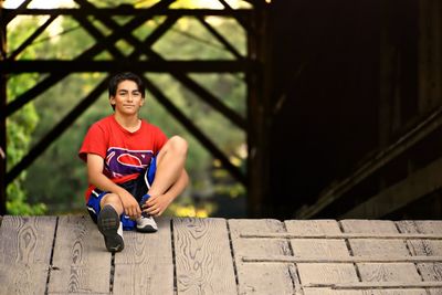 Portrait of young man sitting on wall