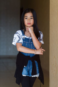 Portrait of a smiling girl standing against wall