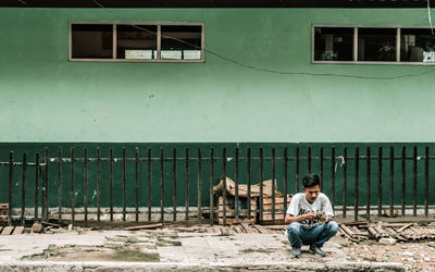 Man sitting on window against building