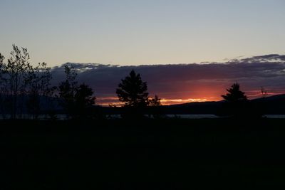 Silhouette trees on landscape against sky at sunset