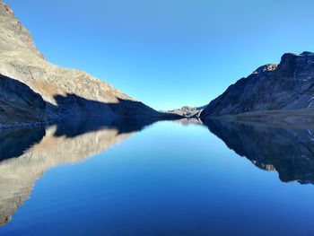 Scenic view of lake and mountains against clear blue sky