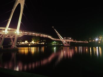 Illuminated bridge over river at night