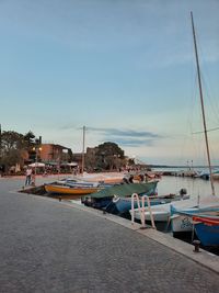 Sailboats moored at harbor against sky